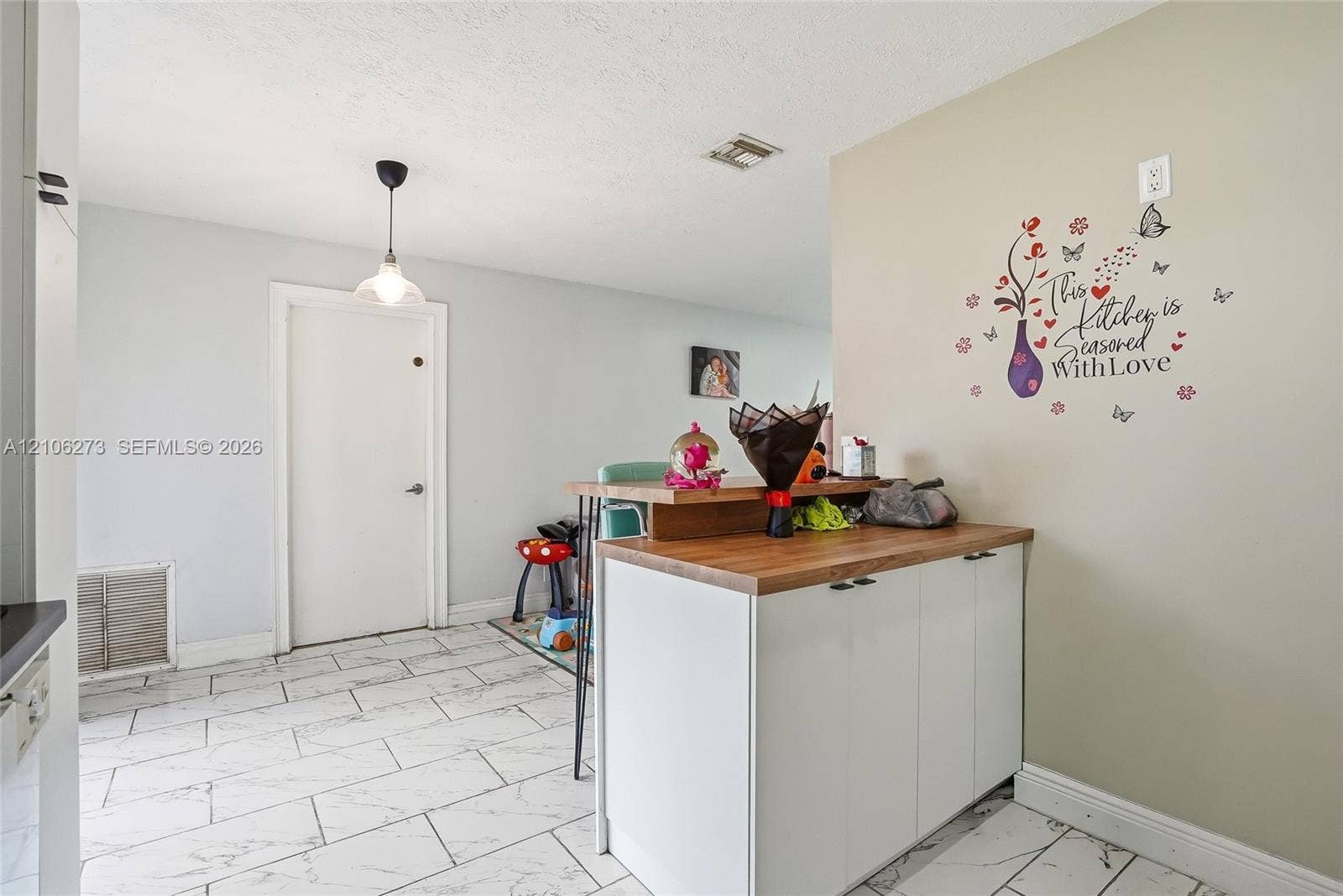 5310 Seagrape Drive, Fort Pierce, FL 34982 White cabinetry with wood-finish countertop, white tile flooring, and pendant lighting