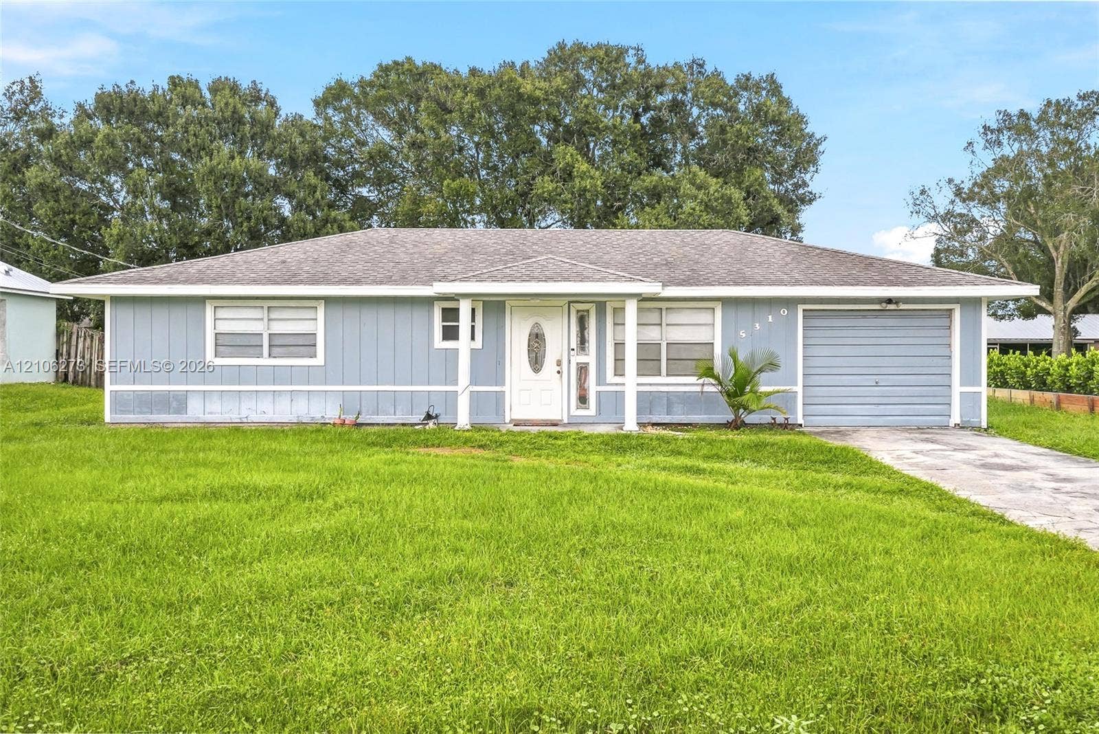 5310 Seagrape Drive, Fort Pierce, FL 34982 Single-story exterior featuring vertical siding, a covered entryway, an attached garage, and a concrete driveway
