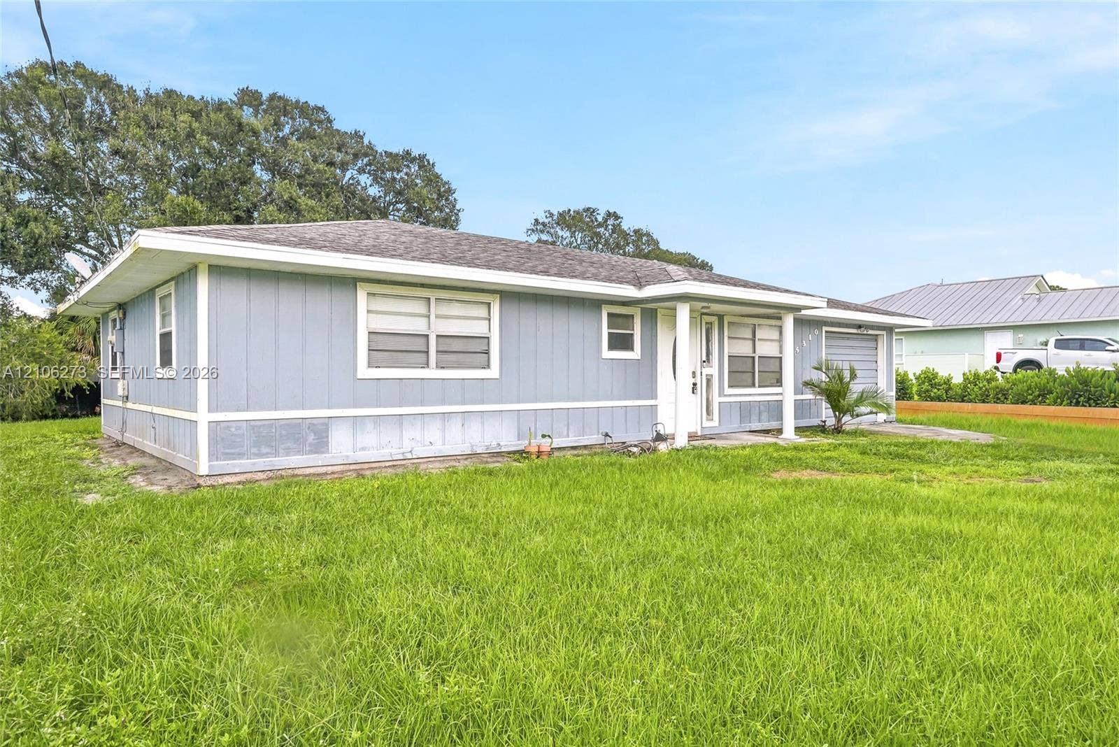 5310 Seagrape Drive, Fort Pierce, FL 34982 Single-story residence featuring light-blue vertical siding, white trim accents, an integrated garage, and a covered front entryway supported by columns