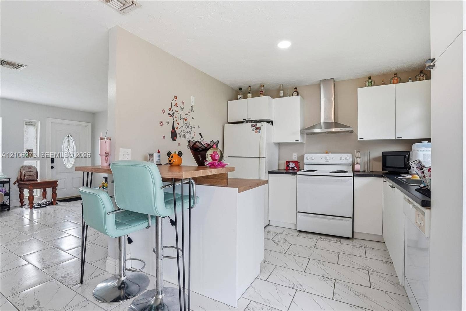 5310 Seagrape Drive, Fort Pierce, FL 34982 Kitchen featuring white cabinetry, solid-surface countertops, a stainless steel range hood, and tile flooring