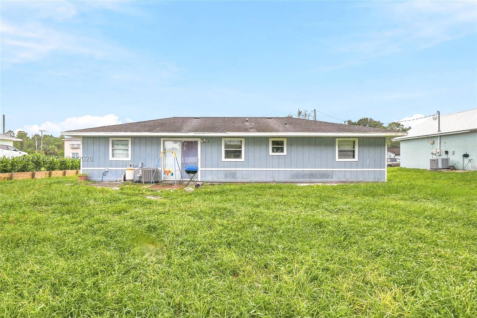 5310 Seagrape Drive, Fort Pierce, FL 34982 Single-story exterior with light blue horizontal siding, hipped roofline, and rear sliding glass door access