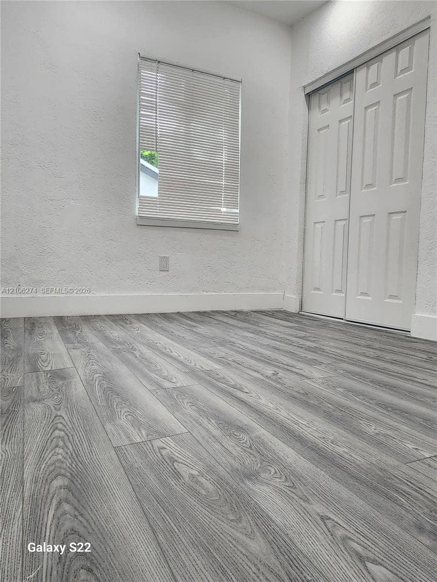 1601 NW 50th Street, Miami, FL 33142 Wood-finish flooring, white textured walls, and dual-panel closet doors