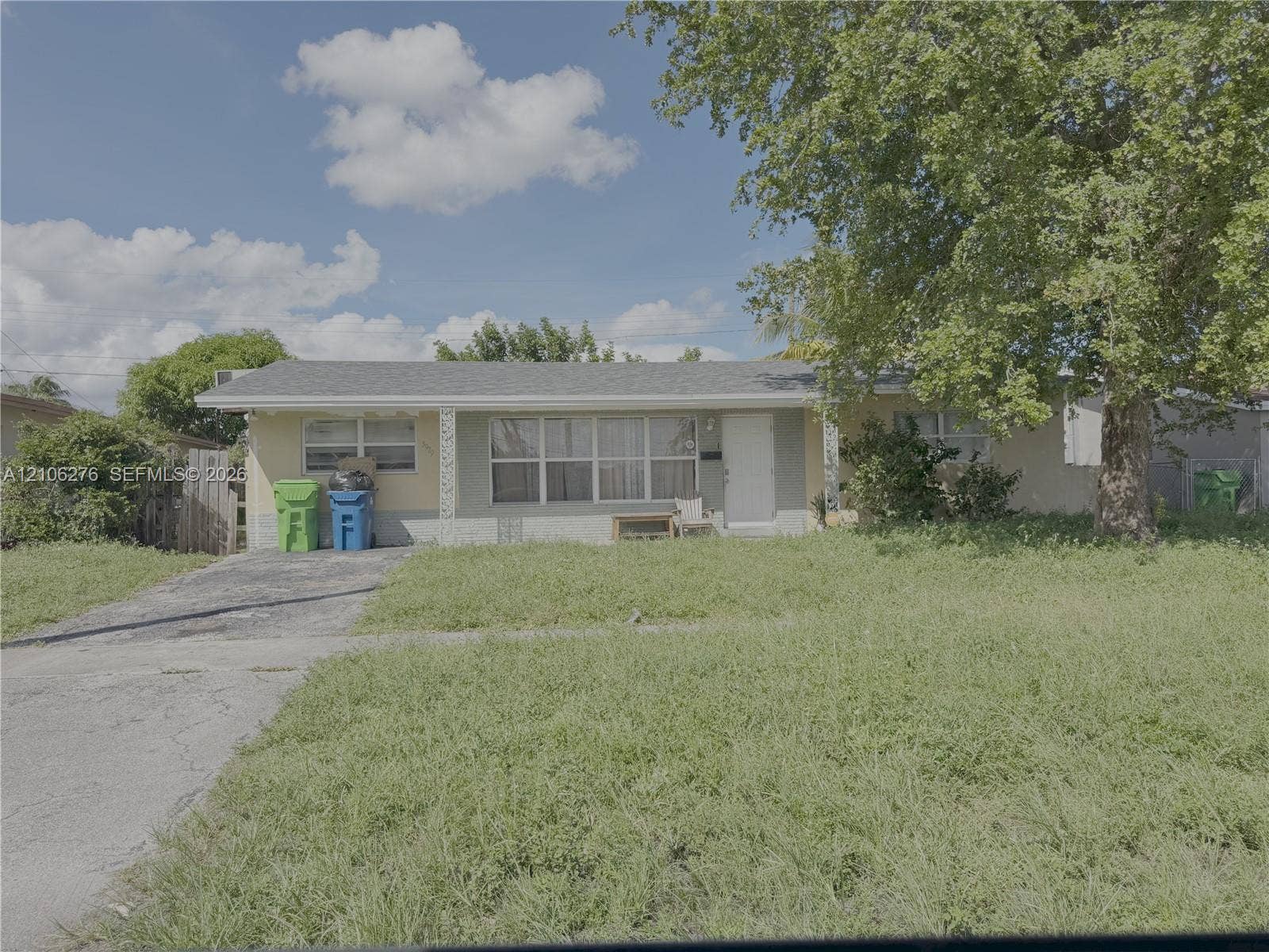 Sunrise, FL 33313 Single-story residence featuring a low-slope roof, multi-pane window configurations, an attached concrete driveway, and mature canopy trees