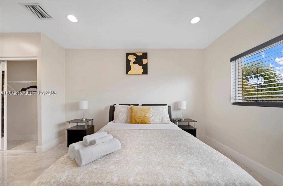 Neutral-toned walls, recessed lighting, polished stone-finish flooring, and a sliding glass closet door with white trim