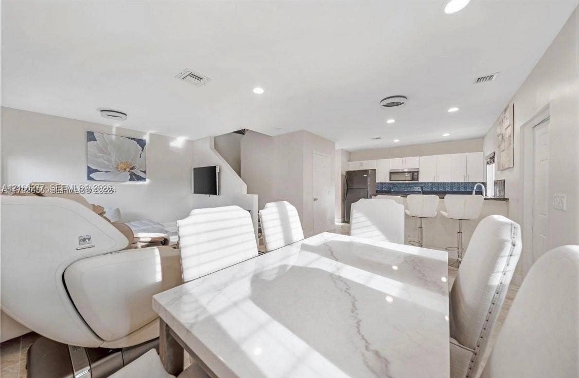 Open-concept interior featuring recessed lighting, a kitchen with flat-panel white cabinetry, and a tiered breakfast bar