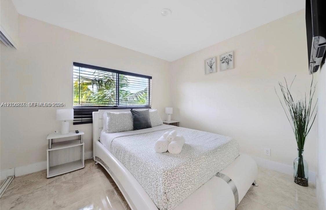 Neutral wall finishes, polished stone-finish tile flooring, and horizontal window blinds