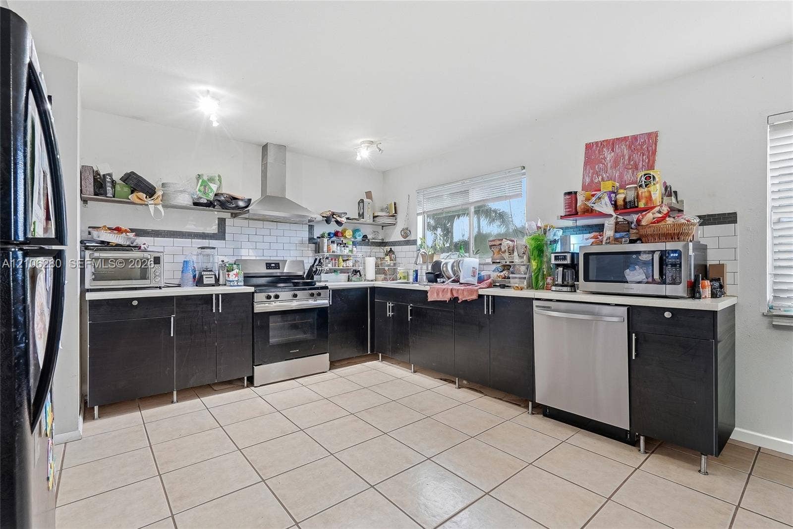 2017 SE Ancora Court, Port St Lucie, FL 34952 Kitchen featuring dark cabinetry, stainless steel appliances, a white tile backsplash, and ceramic tile flooring