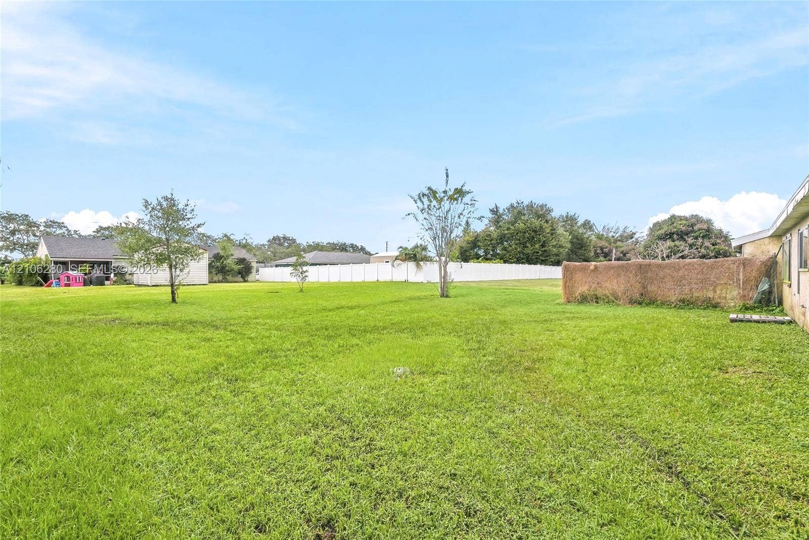 2017 SE Ancora Court, Port St Lucie, FL 34952 Expansive backyard featuring a manicured lawn, perimeter fencing, and mature trees