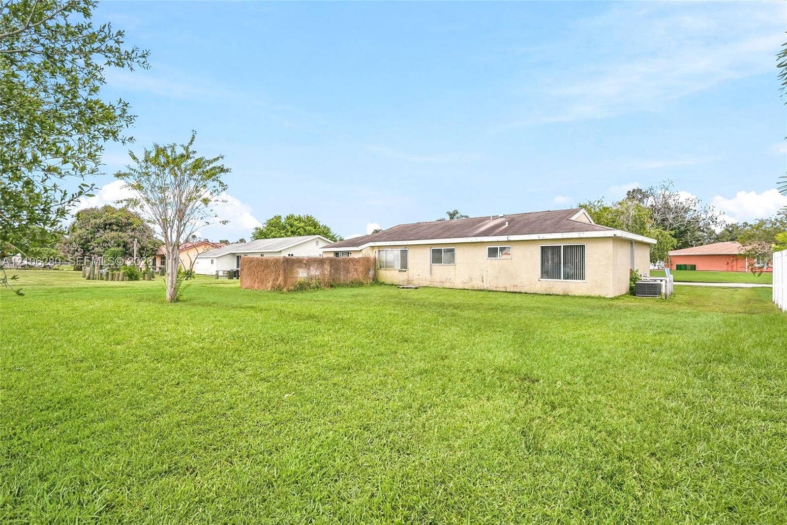 2017 SE Ancora Court, Port St Lucie, FL 34952 Expansive backyard featuring a large grass lawn, mature trees, and a textured exterior finish