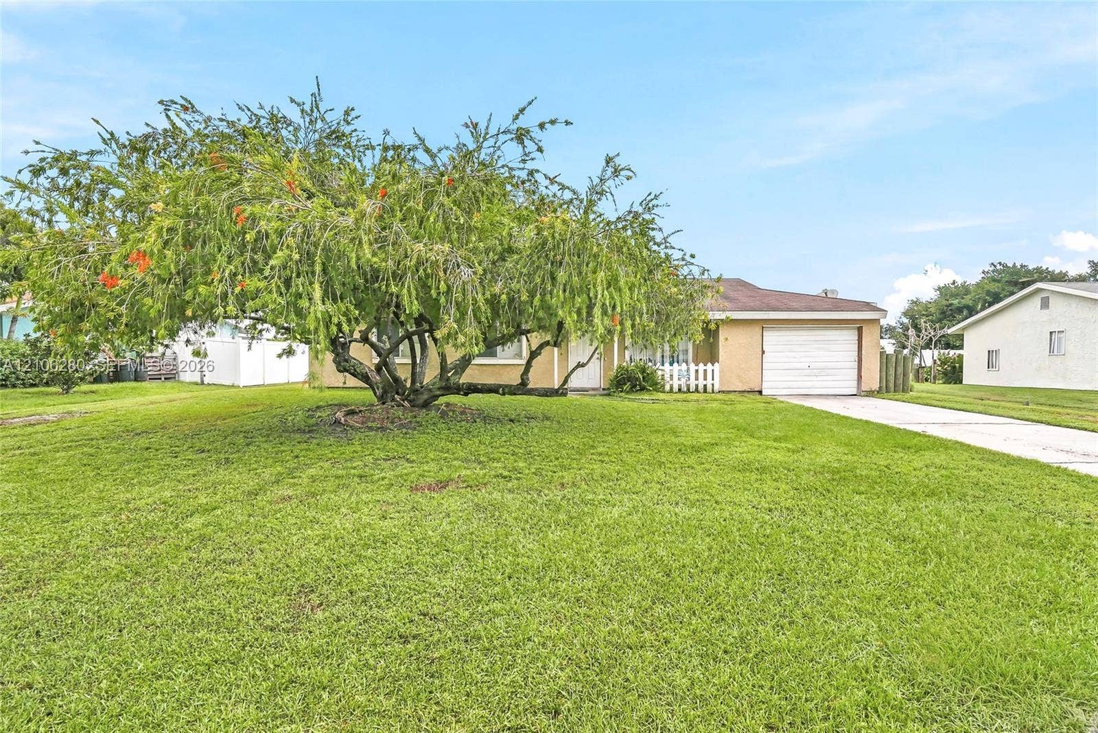 2017 SE Ancora Court, Port St Lucie, FL 34952 Single-story exterior featuring a stucco facade, attached one-car garage, concrete driveway, and mature landscaping
