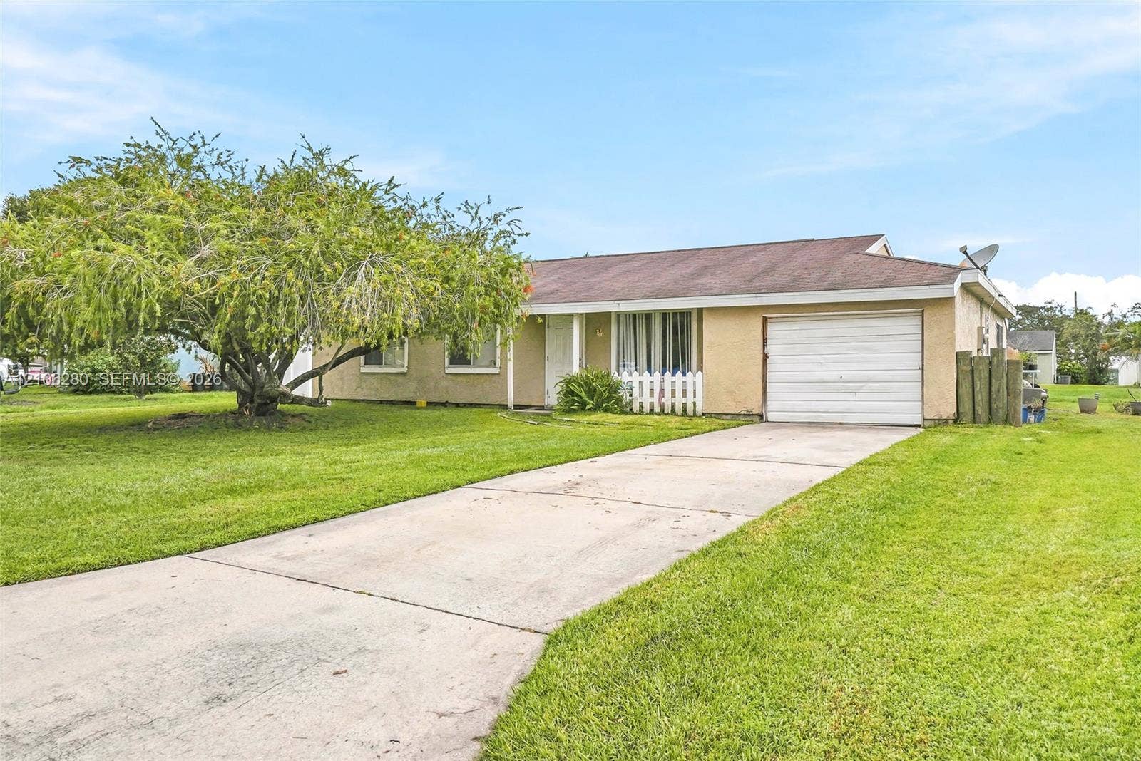 2017 SE Ancora Court, Port St Lucie, FL 34952 Single-story exterior featuring a stucco facade, attached one-car garage, concrete driveway, and mature landscaping