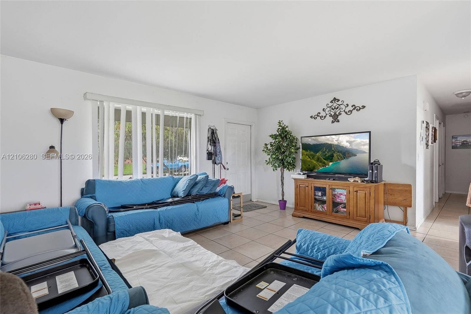 2017 SE Ancora Court, Port St Lucie, FL 34952 Living area featuring neutral tile flooring, expansive window with vertical blinds, and a solid-core entry door