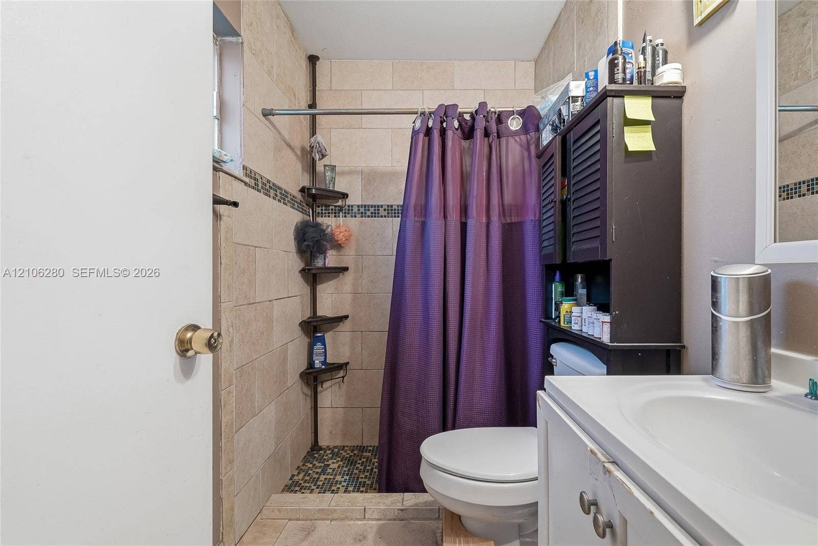 2017 SE Ancora Court, Port St Lucie, FL 34952 Bathroom featuring tile-surround shower stall with mosaic accent inlay, neutral large-format wall tile, and white vanity with integrated sink