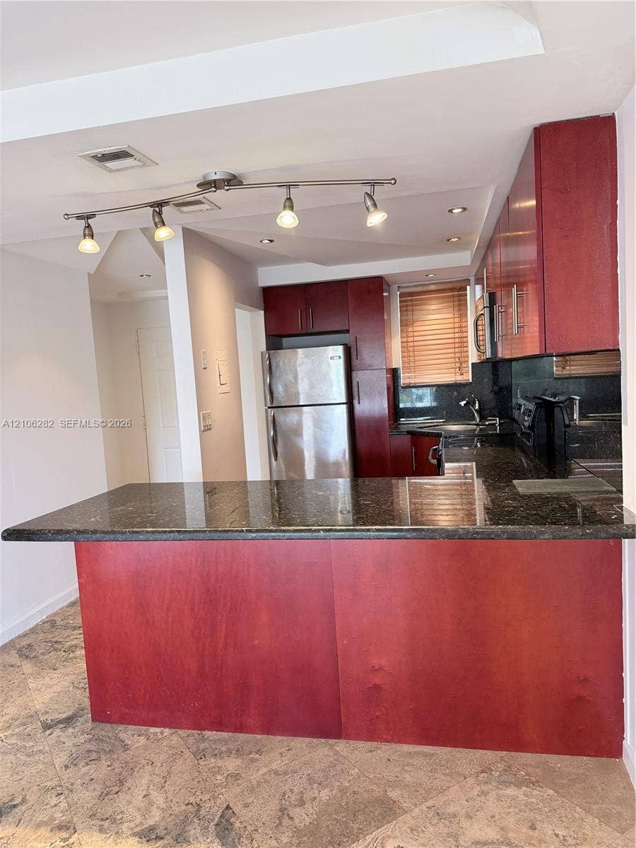 665 NE 83rd Terrace, #210, Miami, Miami, FL 33138 Kitchen featuring dark-toned cabinetry, a peninsula with stone-finish countertops, stainless steel appliances, and track lighting