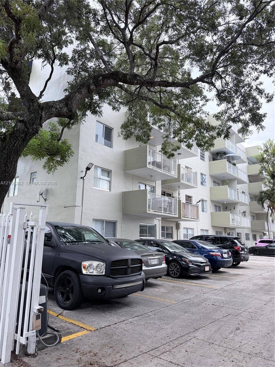 665 NE 83rd Terrace, #210, Miami, Miami, FL 33138 Multi-story exterior featuring a light-toned stucco faade, private balconies with metal railings, and paved surface parking