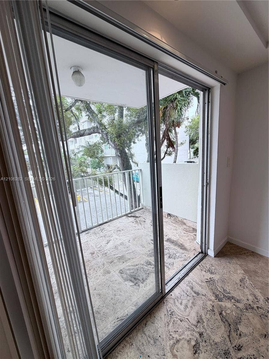 665 NE 83rd Terrace, #210, Miami, Miami, FL 33138 Sliding glass doors opening to a private balcony with stone-finish flooring and a metal railing