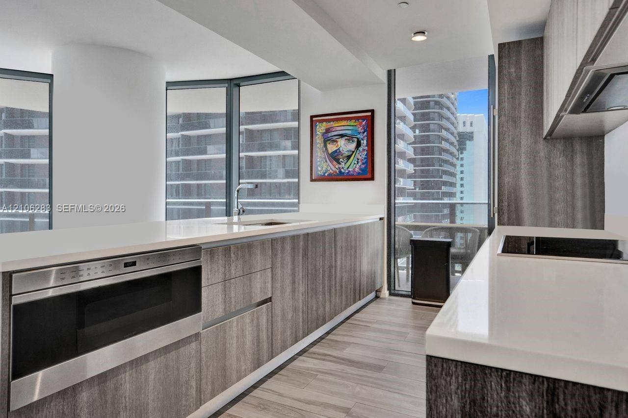 801 S Miami Avenue, #1801, Miami, FL 33130 Kitchen featuring wood-finish cabinetry, stone-surface countertops, built-in stainless steel microwave, integrated stovetop, and floor-to-ceiling windows