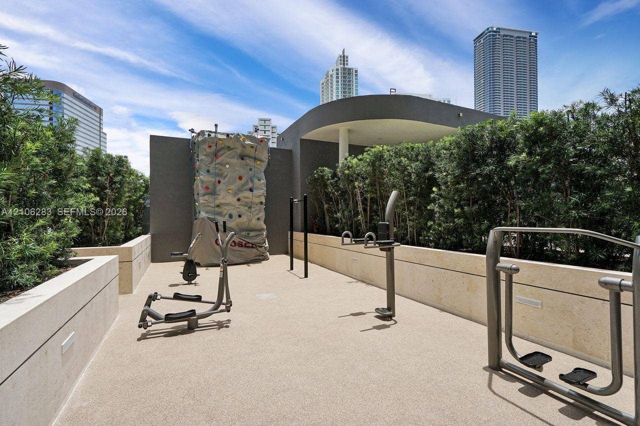 801 S Miami Avenue, #1801, Miami, FL 33130 Outdoor fitness space featuring a climbing wall, anchored exercise equipment, stone-finish retaining walls, and a manicured hedge perimeter