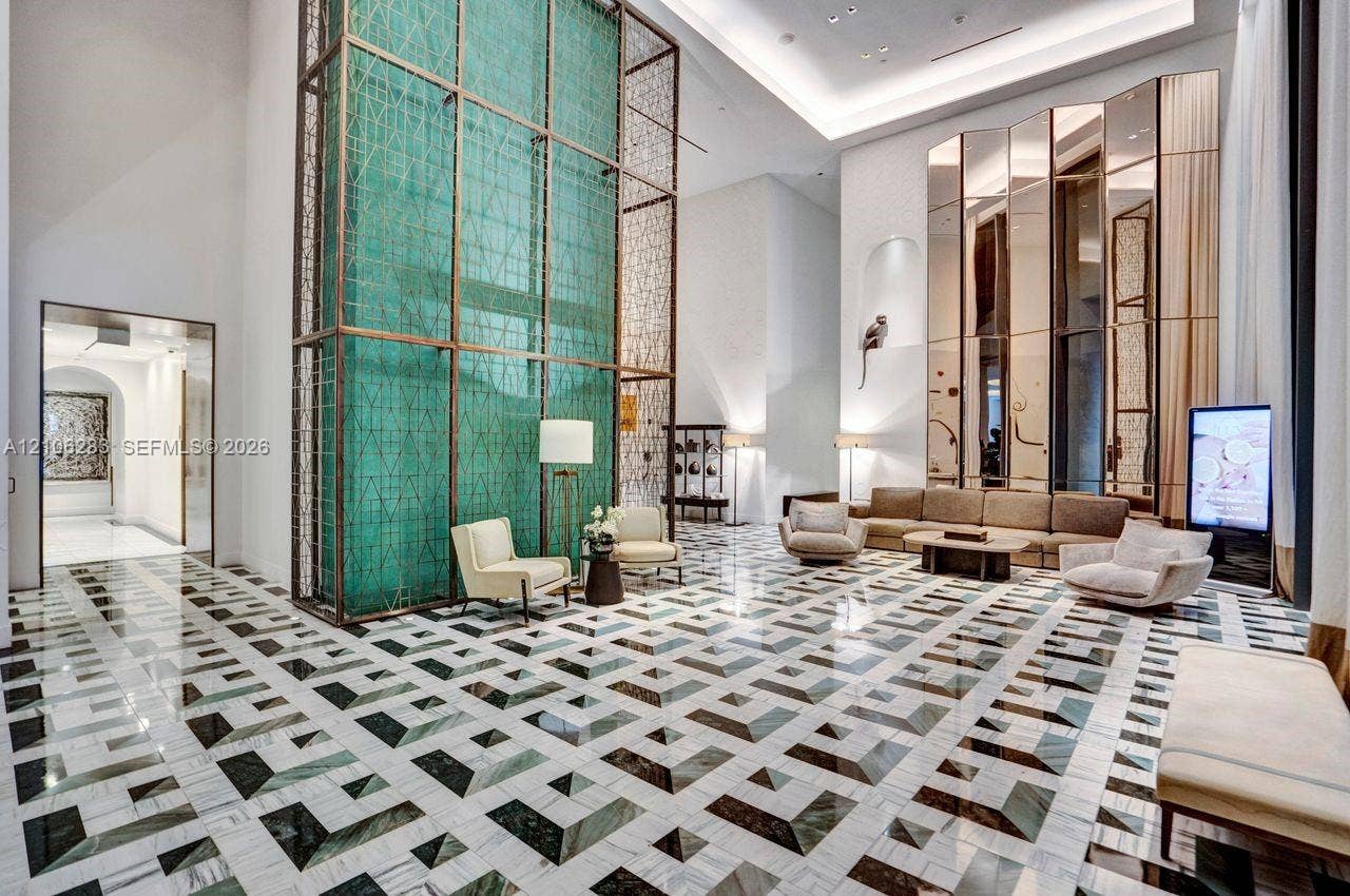 801 S Miami Avenue, #1801, Miami, FL 33130 Grand lobby featuring double-height ceilings, a floor-to-ceiling metal latticework feature wall, geometric stone tile flooring, and full-height mirrored wall panels