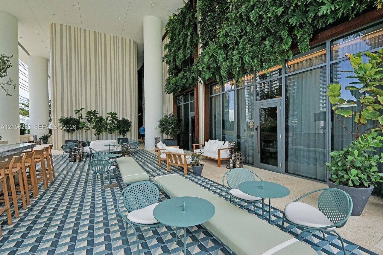 801 S Miami Avenue, #1801, Miami, FL 33130 Covered outdoor terrace featuring geometric patterned tile flooring, floor-to-ceiling glass paneling, vertical green wall accents, and structural columns