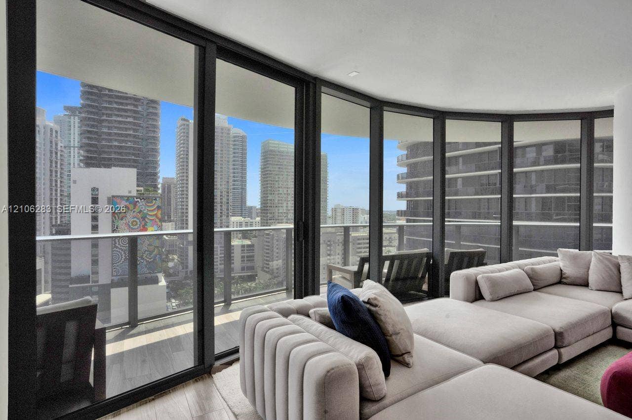 801 S Miami Avenue, #1801, Miami, FL 33130 Floor-to-ceiling glass walls, wrap-around balcony with a metal railing, and neutral wood-finish flooring