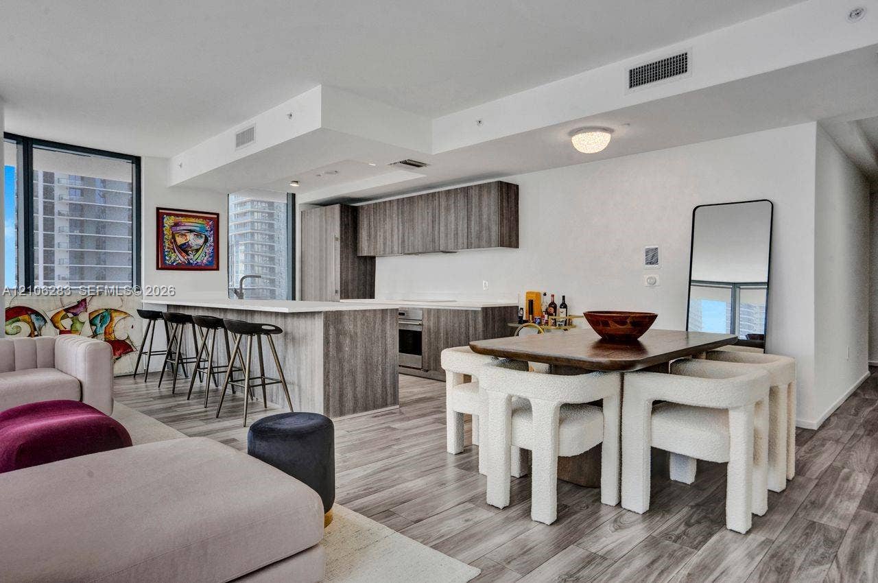801 S Miami Avenue, #1801, Miami, FL 33130 Open-concept kitchen featuring flat-panel wood-finish cabinetry, a large kitchen island with countertop seating, stainless steel appliances, and wood-finish flooring throughout