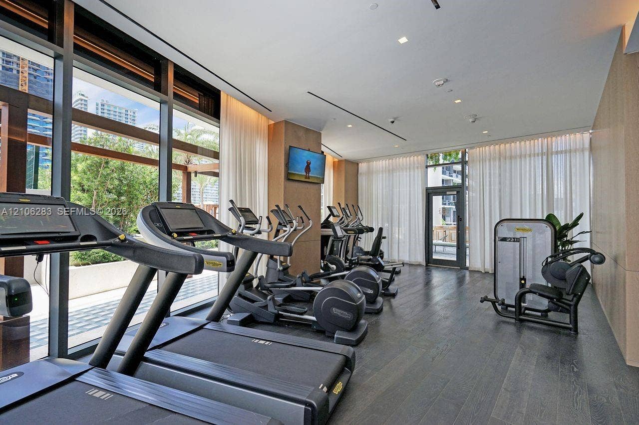 801 S Miami Avenue, #1801, Miami, FL 33130 Fitness center featuring dark wood-finish flooring, floor-to-ceiling windows, recessed lighting, and wall-mounted neutral paneling