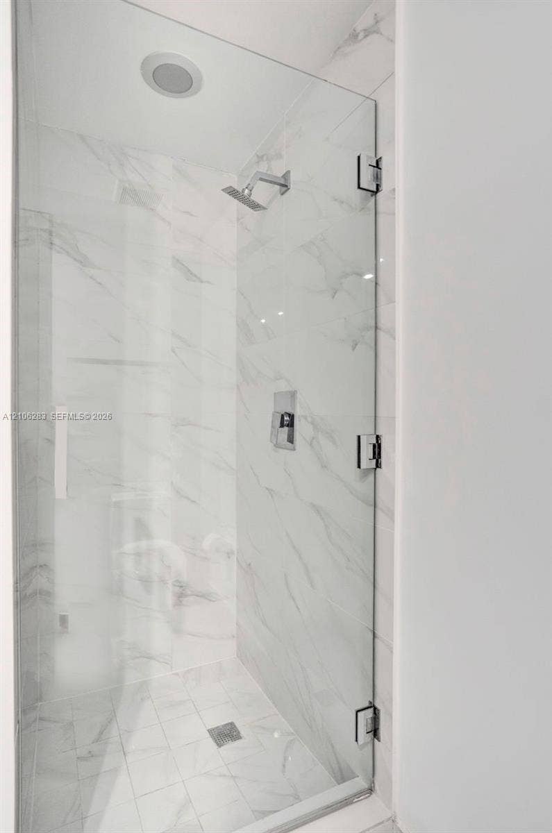 801 S Miami Avenue, #1801, Miami, FL 33130 Walk-in shower featuring a frameless glass door, wall-to-wall stone-finish tile, recessed ceiling light, and polished chrome fixtures