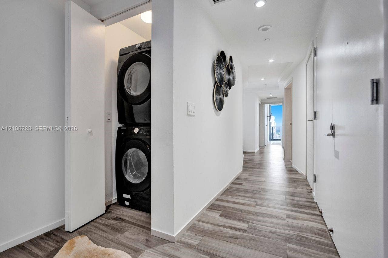 801 S Miami Avenue, #1801, Miami, FL 33130 Stacked laundry unit housed within a dedicated closet, featuring wood-finish flooring and recessed ceiling lighting