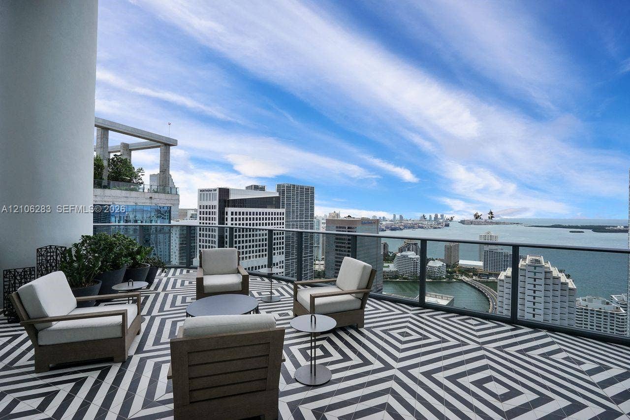 801 S Miami Avenue, #1801, Miami, FL 33130 Expansive covered terrace featuring black and white geometric tile flooring, a glass-panel railing, and panoramic water and city skyline outlooks