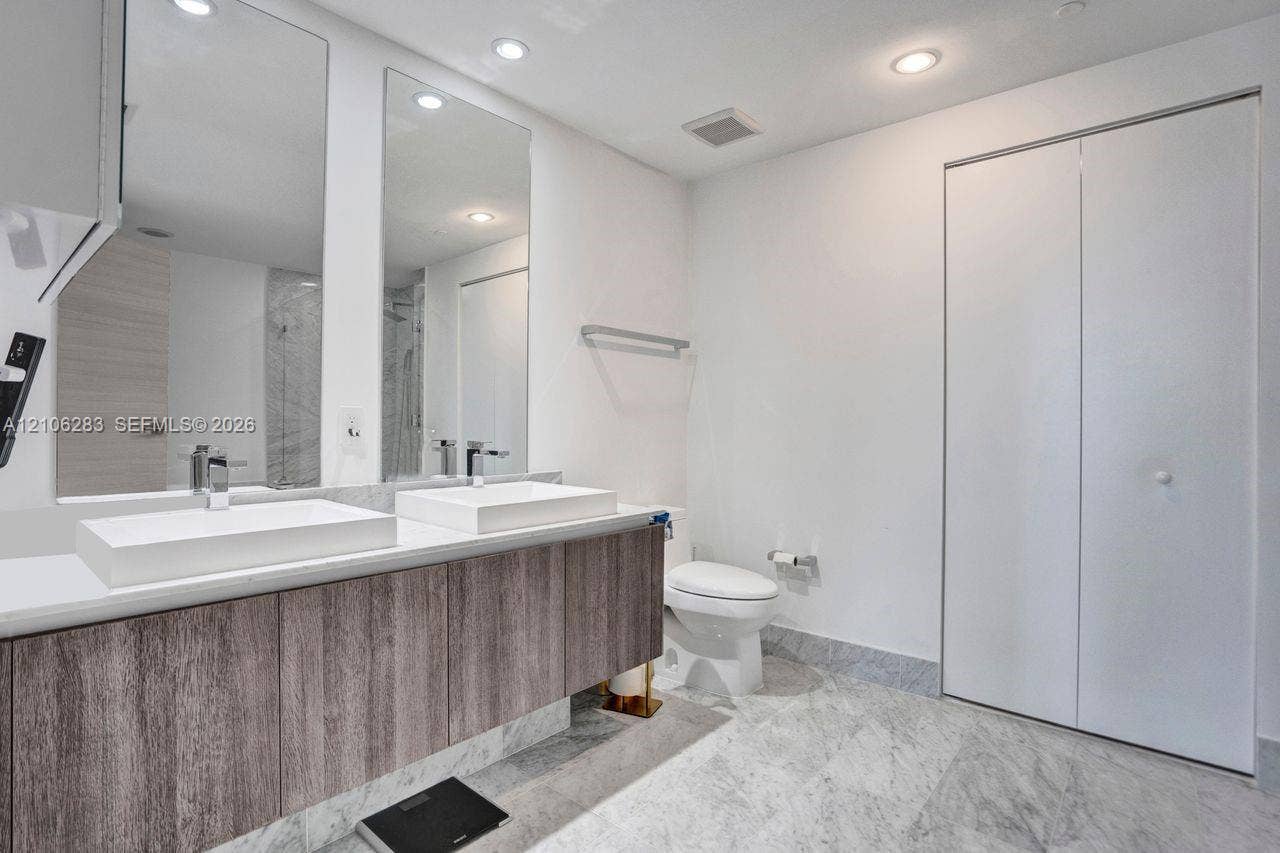 801 S Miami Avenue, #1801, Miami, FL 33130 Floating vanity with dual rectangular vessel sinks, stone-finish flooring, full-height wall mirrors, and bifold closet doors