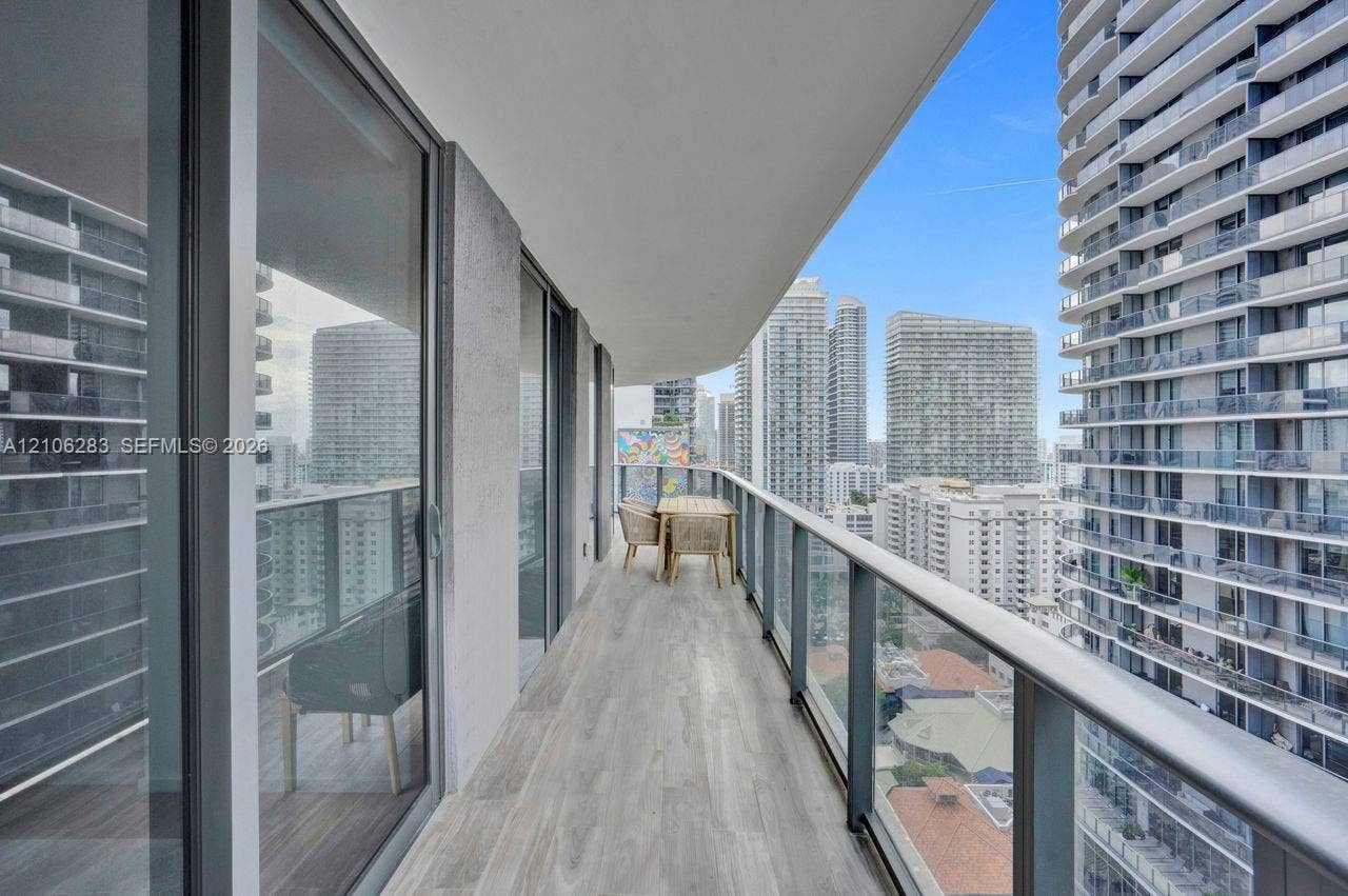 801 S Miami Avenue, #1801, Miami, FL 33130 Covered balcony featuring wood-finish flooring, full-height sliding glass doors, and a glass-paneled railing