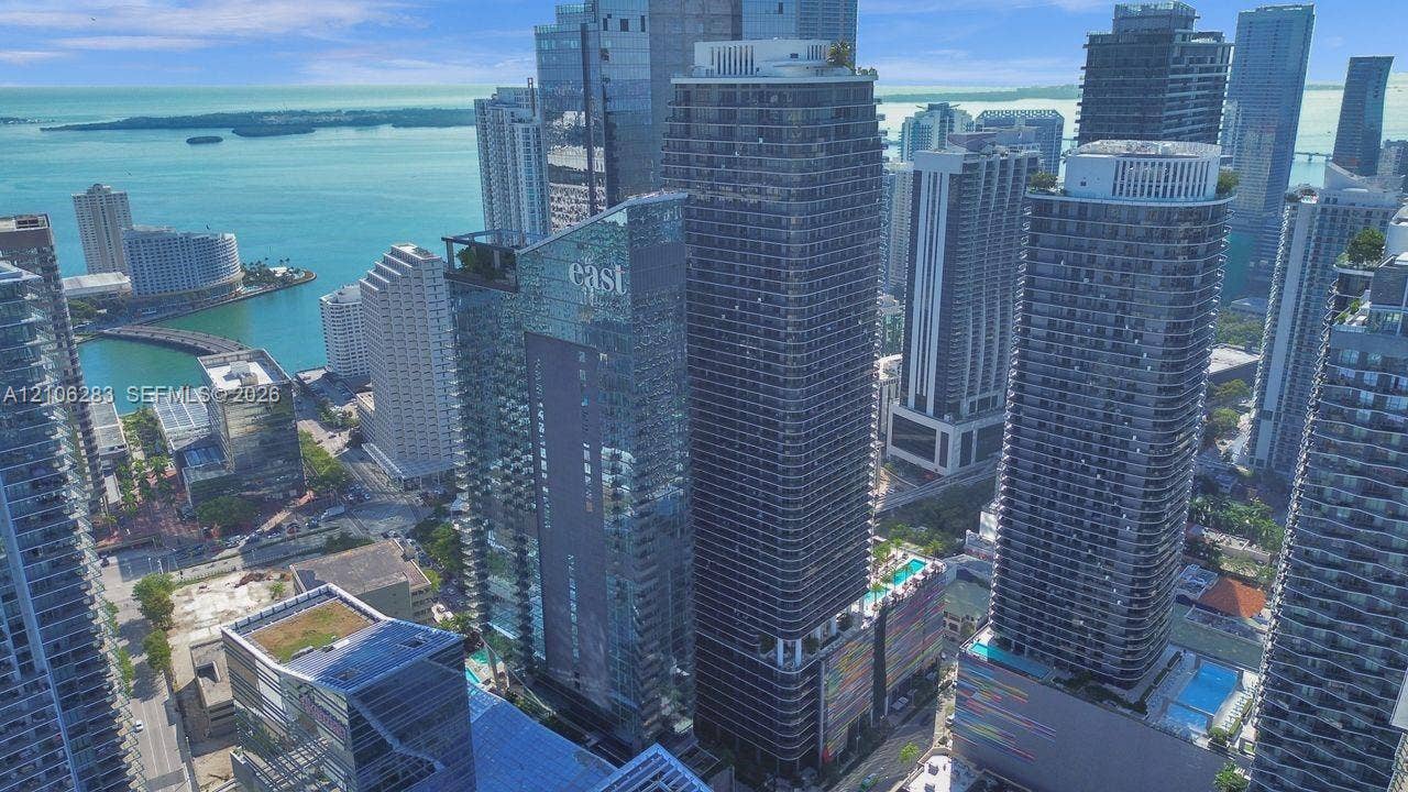 801 S Miami Avenue, #1801, Miami, FL 33130 Aerial perspective of a high-rise urban skyscraper featuring floor-to-ceiling glass paneling, structured balconies, a rooftop pool, and proximity to the waterfront
