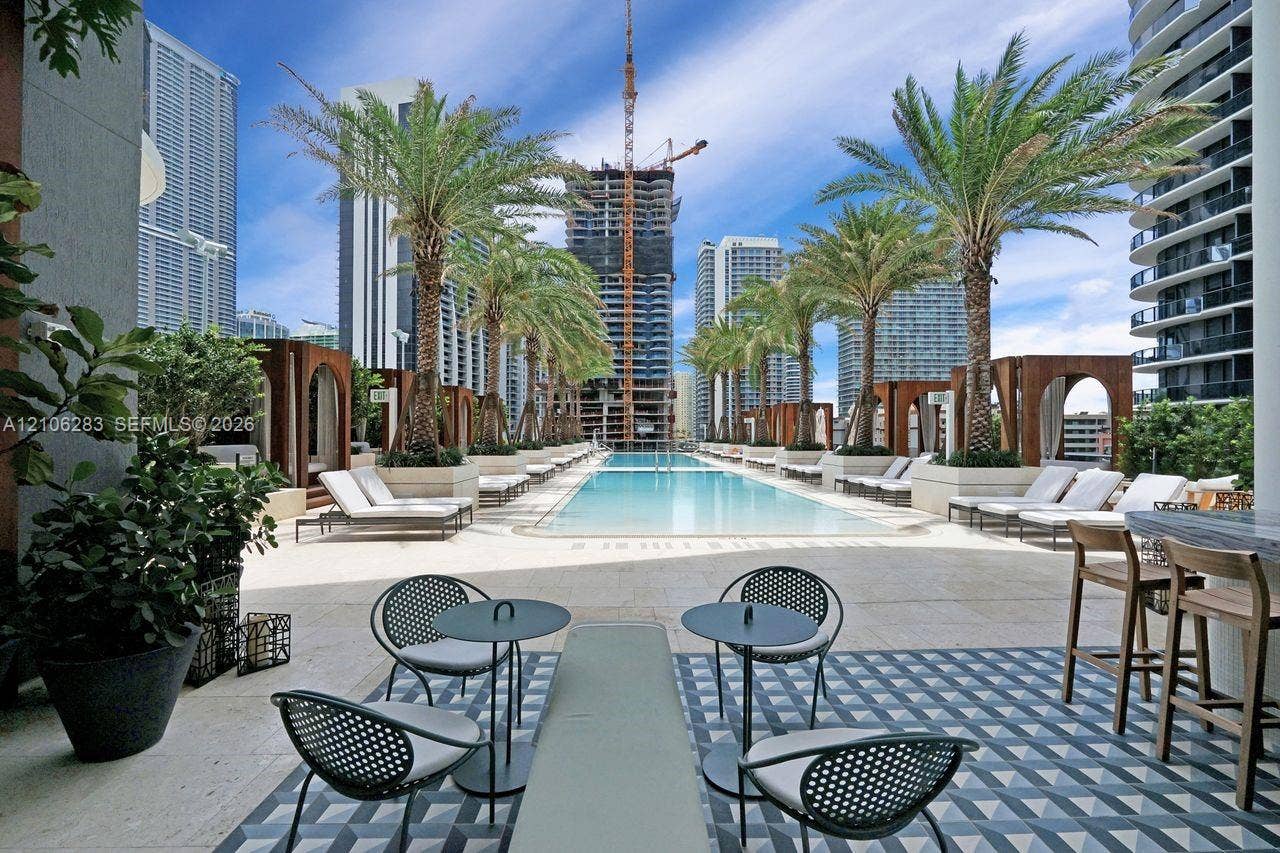 801 S Miami Avenue, #1801, Miami, FL 33130 Pool deck featuring a linear swimming pool, geometric tile flooring, wood-framed cabanas, and perimeter palm trees