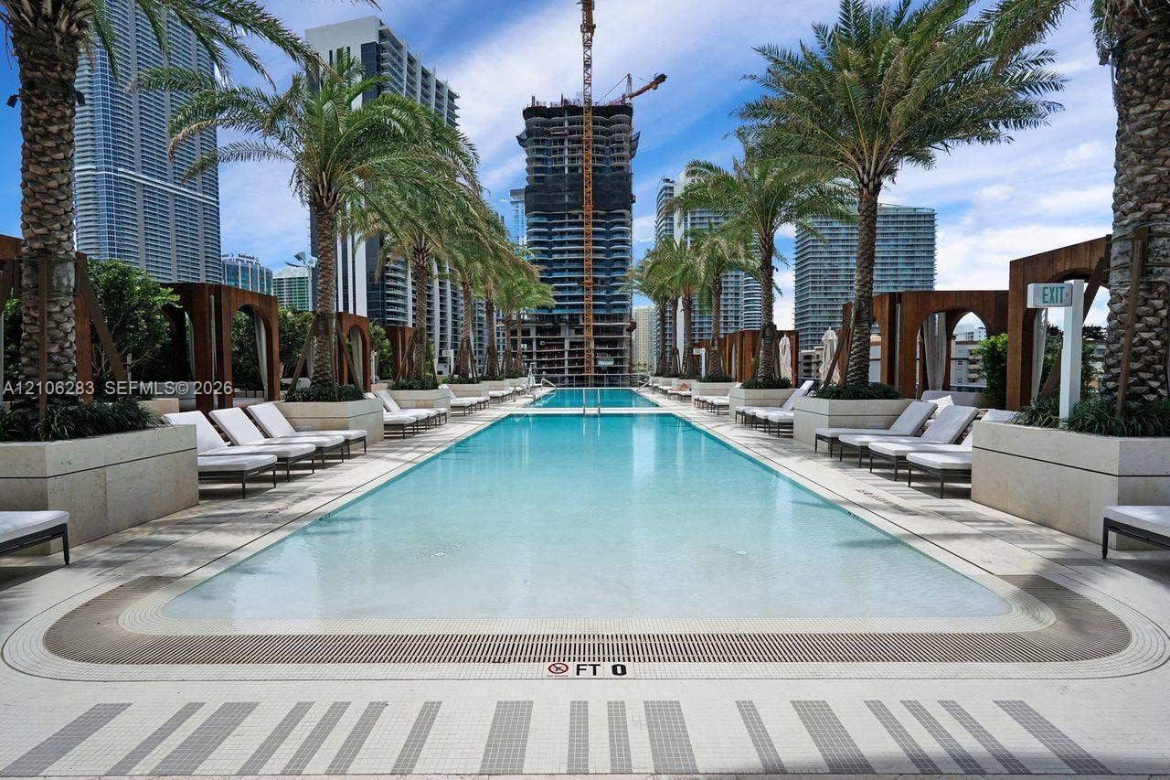 801 S Miami Avenue, #1801, Miami, FL 33130 Rectangular swimming pool featuring stone-tile decking, built-in wooden cabanas, mature palm trees, and integrated landscaping planters