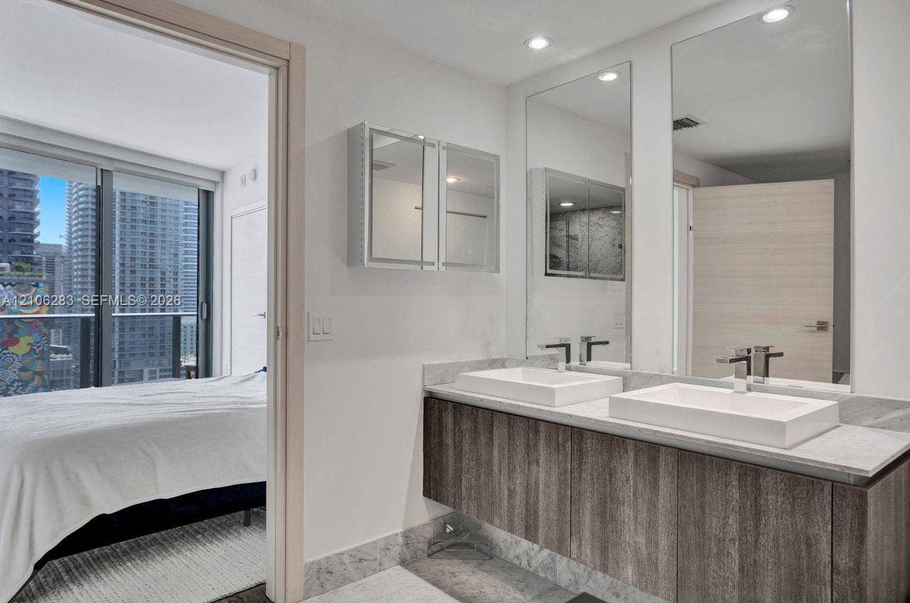 801 S Miami Avenue, #1801, Miami, FL 33130 Floating wood-finish vanity with dual rectangular vessel sinks, stone-surface countertop, full-height wall mirrors, and recessed lighting