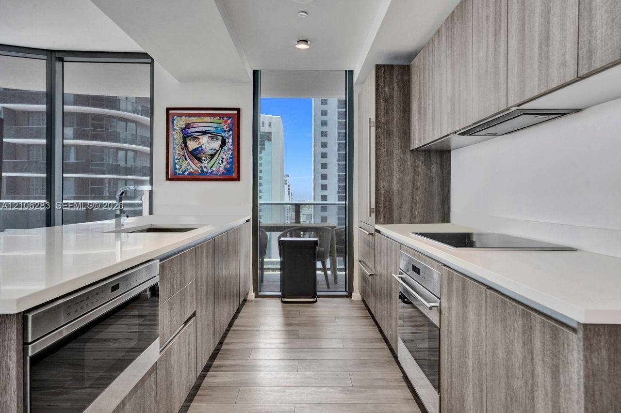 801 S Miami Avenue, #1801, Miami, FL 33130 Galley kitchen featuring wood-finish cabinetry, quartz countertops, integrated stainless steel appliances, and wood-finish flooring