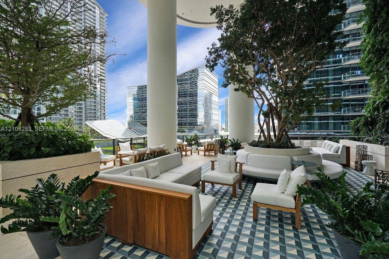 801 S Miami Avenue, #1801, Miami, FL 33130 Covered outdoor terrace featuring geometric patterned tile flooring, structural concrete pillars, and integrated stone planters with mature landscaping
