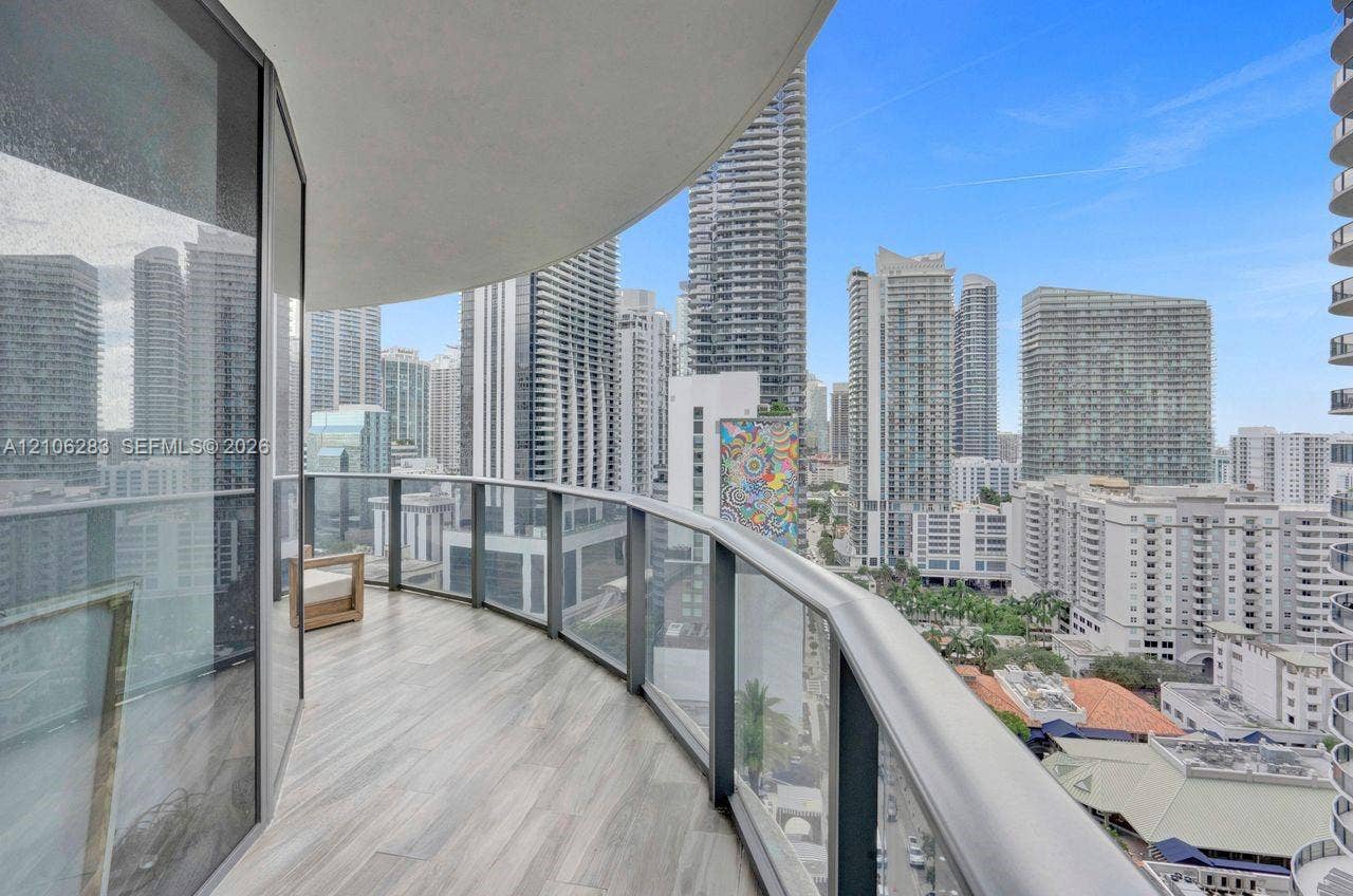801 S Miami Avenue, #1801, Miami, FL 33130 Curved balcony featuring wood-finish flooring, floor-to-ceiling glass railings, and expansive urban skyline scenery