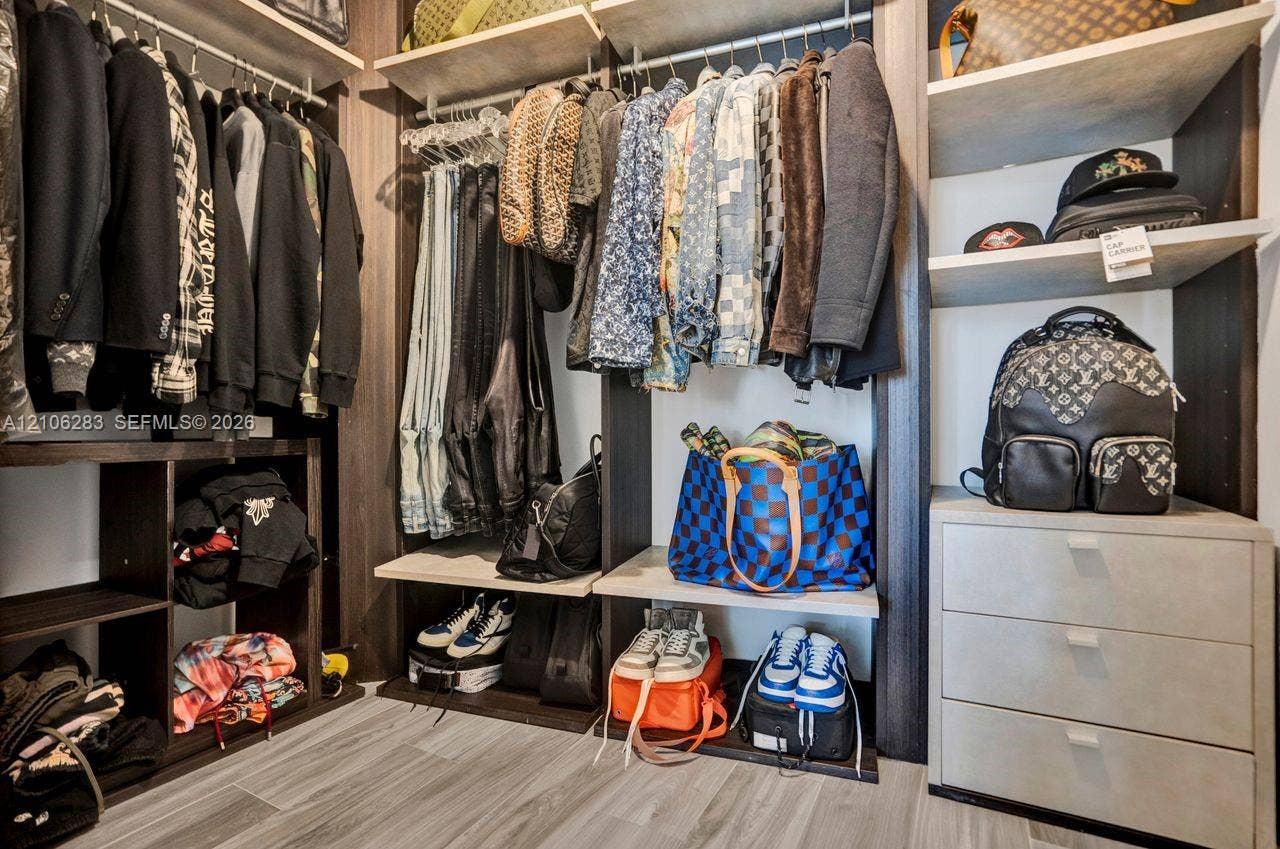 801 S Miami Avenue, #1801, Miami, FL 33130 Custom walk-in closet featuring dark wood-finish shelving, multi-level hanging rods, built-in open cubbies, a three-drawer storage unit, and wood-finish flooring