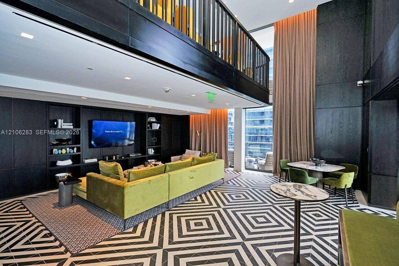 801 S Miami Avenue, #1801, Miami, FL 33130 Double-height living area featuring floor-to-ceiling windows, built-in floor-to-ceiling cabinetry, a mezzanine level with black metal railing, and patterned geometric floor tile