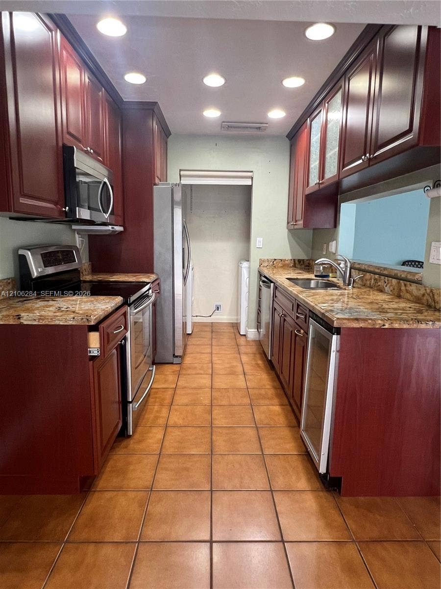 11824 SW 123rd Avenue, #., Miami, Miami, FL 33186 Kitchen featuring stained wood cabinetry, stone countertops, stainless steel appliances, a built-in wine refrigerator, and recessed lighting