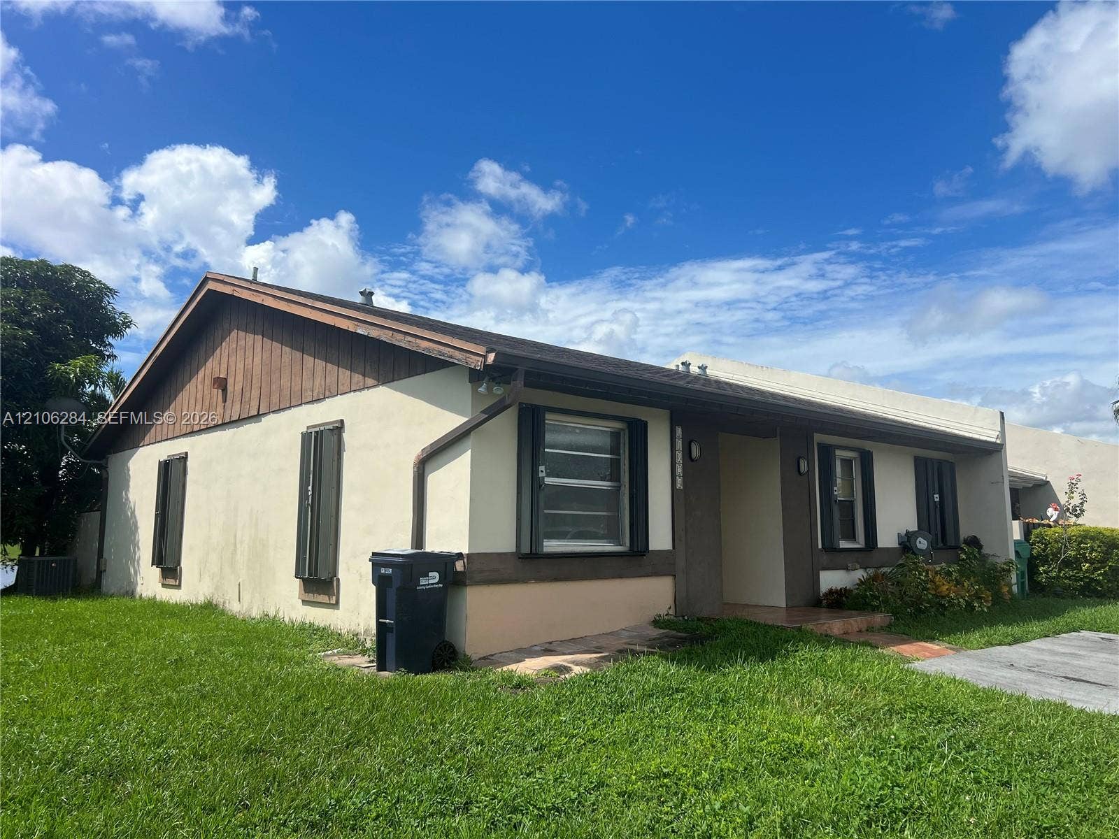 11824 SW 123rd Avenue, #., Miami, Miami, FL 33186 Single-story residence featuring a low-slope roof, stucco exterior, vertical wood-panel siding, and metal window shutters