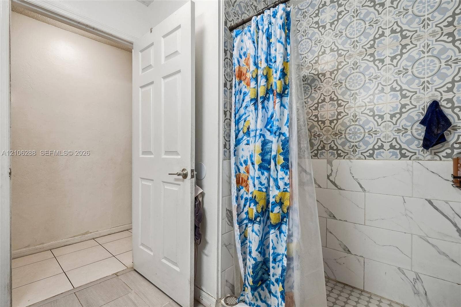 Shower surround featuring patterned tile accents, subway-style wall tile with vein detailing, and hexagonal floor tile
