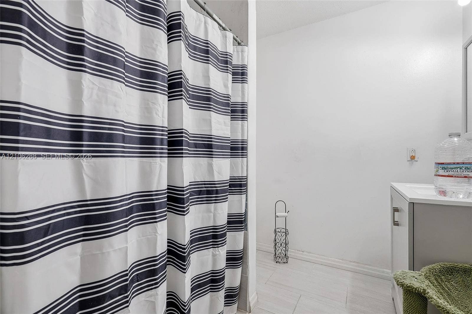 Bathroom featuring light-toned tile flooring and a white vanity with a rectangular sink