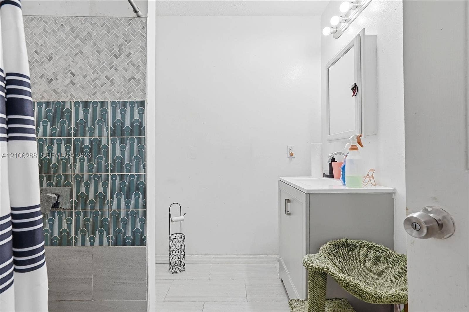 Bathroom featuring patterned wall tiling, light-tone floor tiling, a vanity with an integrated countertop, and a built-in mirrored medicine cabinet