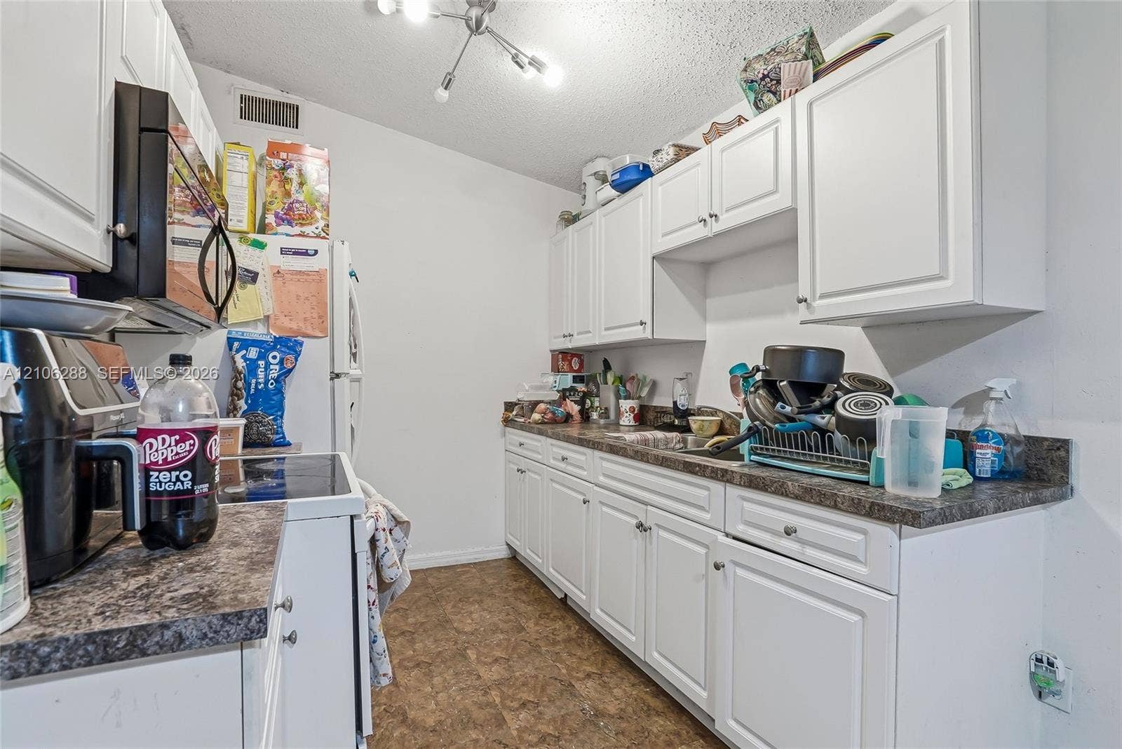 Kitchen featuring white shaker-style cabinetry, laminate countertops, a dual-basin stainless steel sink, and a multi-arm ceiling light fixture