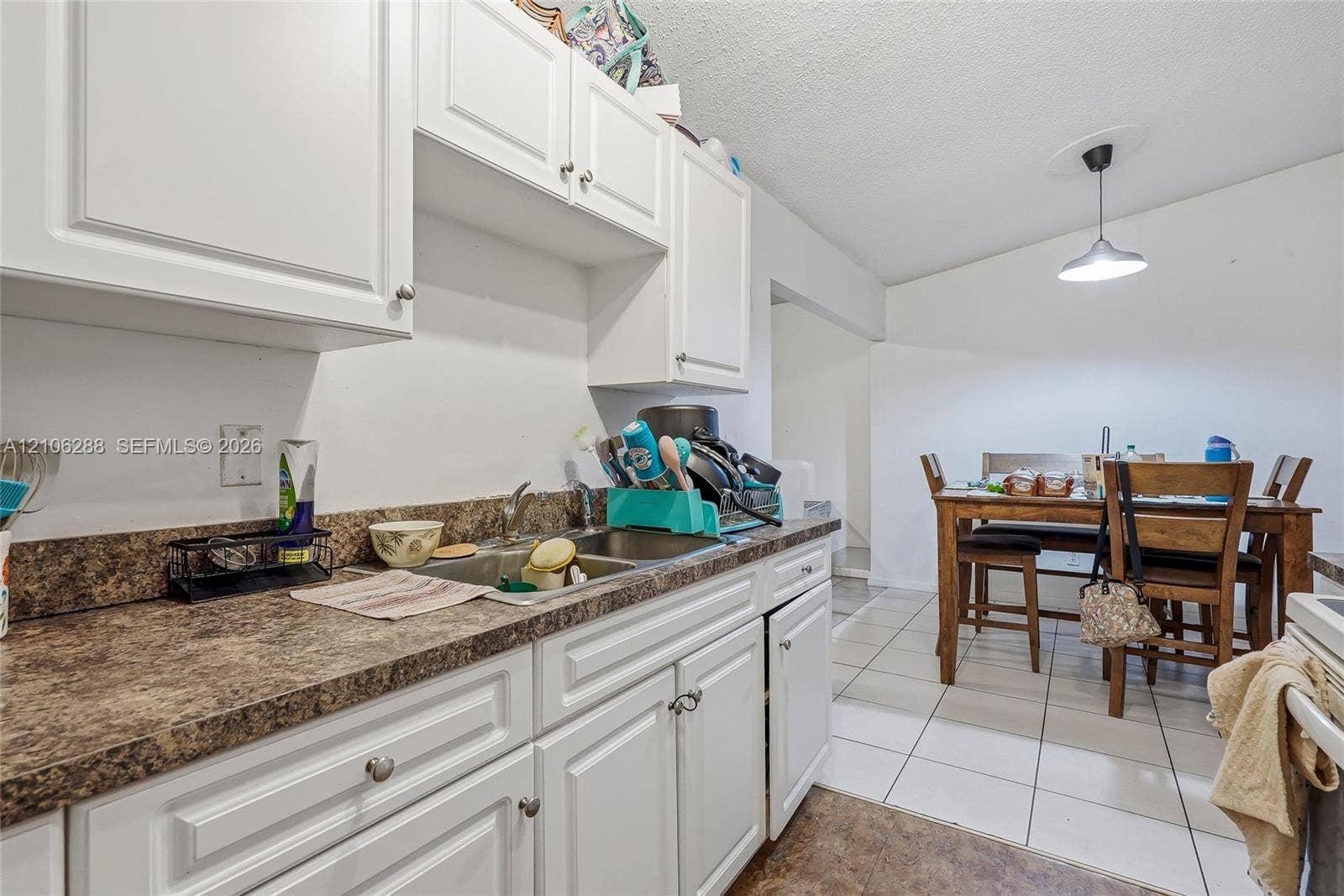 Kitchen featuring white shaker-style cabinetry, a dual-basin stainless steel sink, and a high-contrast laminate countertop
