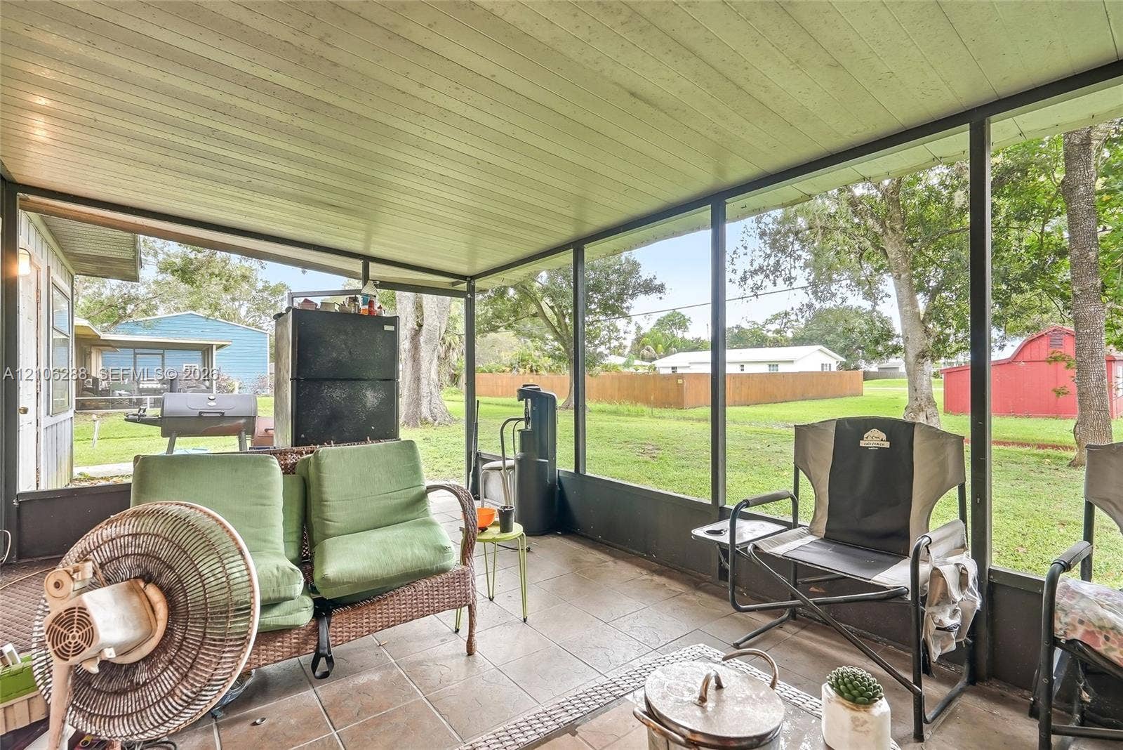 Screened-in porch featuring a neutral tile floor, a painted metal ceiling, and full-height mesh screening