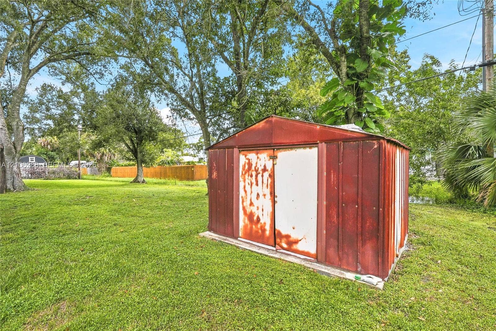 Expansive yard featuring mature trees and a metal storage structure